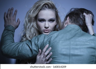 Young Woman Is Pulling Her Boyfriend To Her By His Hair, Man Standing With His Back At The Camera While Embracing His Lover