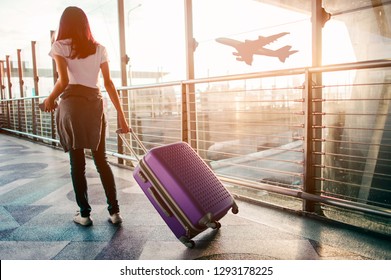 Young woman pulling suitcase in  airport terminal. Copy space