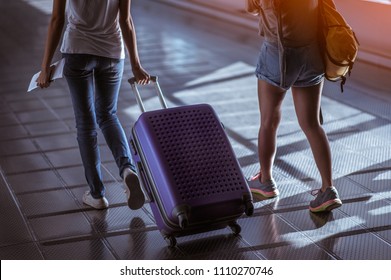 Young woman pulling suitcase in modern airport terminal. Travelling guy with his luggage while waiting for transport. Rear view. Copy space