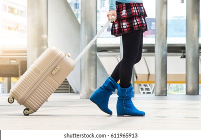 Young woman pulling suitcase in modern airport terminal, Tourist walking away with his luggage while waiting for transport, Rear view. Copy space