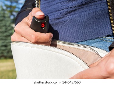 A Young Woman Pulls A Can Of Tear Gas Or Bottle Of Pepper Spray Out Of Her Purse. Means Of Self-defense. Selective Focus, Close-up. 