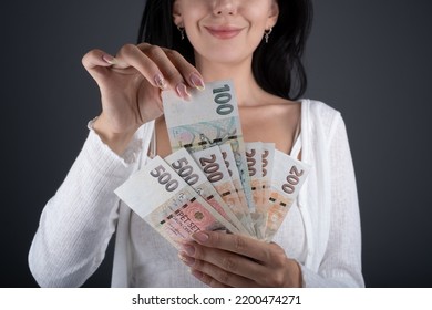 A young woman pulls out a 100 Czech crown bill. Woman hold Fan of Cash Czech republic koruna currency. Czechia finance concept. CZK small nominal banknotes.