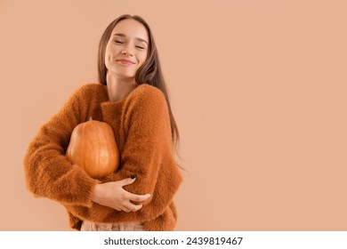 Young woman with pumpkin on beige background - Powered by Shutterstock