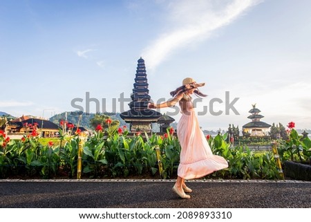Young woman  at the Pura Ulun Danu Bratan, Bali. Hindu temple surrounded by flowers on Bratan lake, Bali.