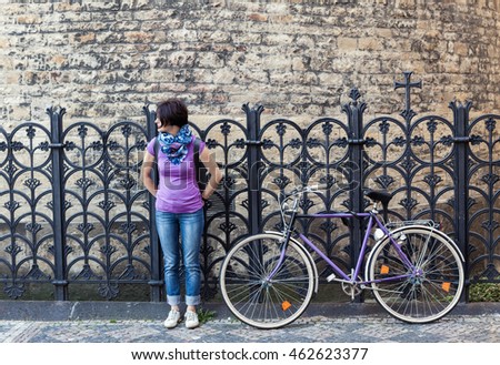Young woman in purple shirt and purple vintage bicycle on the street in Prague, Czech Republic