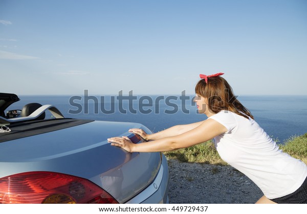 Young woman push the\
car runs out of gas.