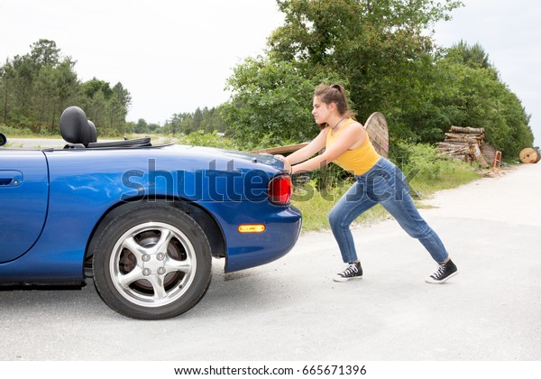 young woman pushing car
