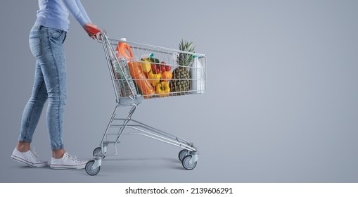 Young woman pushing a full shopping cart, supermarket and grocery shopping banner, blank copy space - Shutterstock ID 2139606291