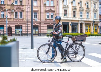 young woman pushing her electric bicycle on the street