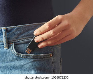 Young woman pushing usb flash drive into a jeans pocket