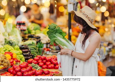 Young Woman Puts Fruits And Vegetables In Cotton Produce Bag At Food Market. Reusable Eco Bag For Shopping. Zero Waste Concept.