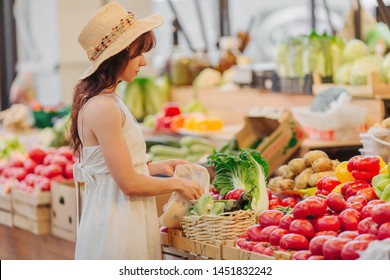 Young Woman Puts Fruits And Vegetables In Cotton Produce Bag At Food Market. Reusable Eco Bag For Shopping. Zero Waste Concept.