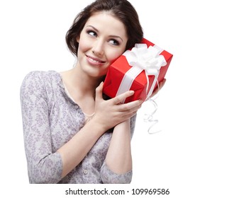 Young Woman Puts Her Ear To The Present Wrapped In Red Paper, Isolated On White