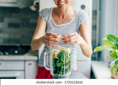 A Young Woman Puts The Ingredients For A Smoothie In A Blender Bowl. Healthy Eating Concept.