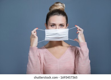 Young woman puts on a medical mask. Symptoms of influenza, fever, pandemic, epidemic. - Shutterstock ID 1693457365