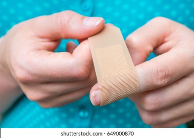 Young woman puts a plaster on her injured finger