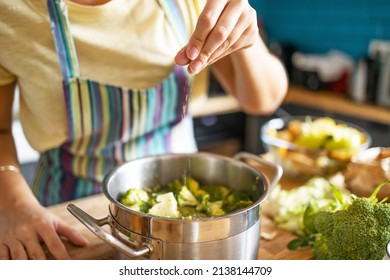 Young woman puts sea salt into boiling pot
 - Powered by Shutterstock