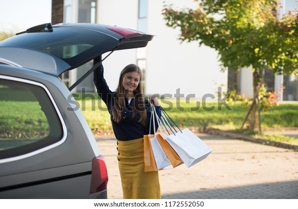 young woman puts\
shopping bags in the car