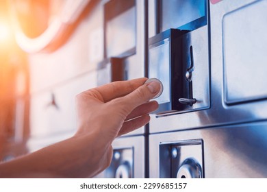 Young woman putting coin in washing machine at laundry - Shutterstock ID 2299685157