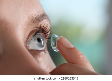 Young woman putting contact lens in her eye on blurred background, closeup - Shutterstock ID 2189263545