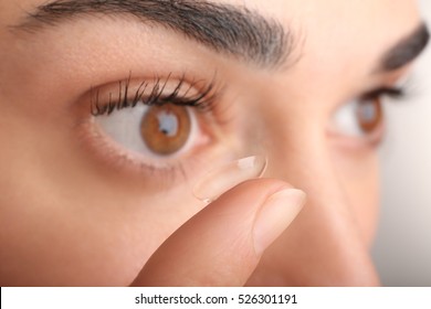 Young woman putting contact lens in her eye, close up view. Medicine and vision concept