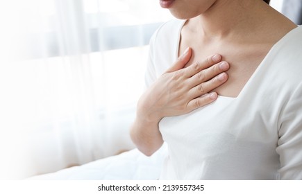 Young woman putting her hand on her chest. Having a pain in chest, Gastroesophageal Reflux Disease  have frequent belching. Healthcare medical concept.  - Shutterstock ID 2139557345