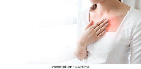 Young woman putting her hand on her chest. Having a pain in chest, Gastroesophageal Reflux Disease  have frequent belching. Healthcare medical concept.  - Shutterstock ID 2153769405