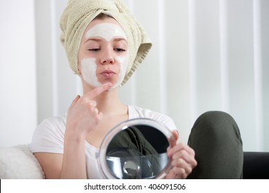 Young Woman Putting Lotion On Her Face At Home