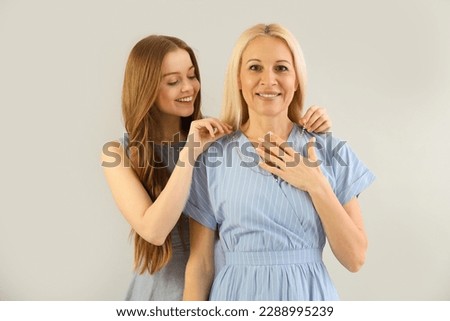 Young woman putting necklace around her mother's neck on grey background ストックフォト © 