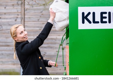 Young Woman Putting Old Or Used Clothes Into Donation Bin