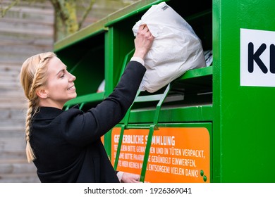 Young Woman Putting Old Or Used Clothes Into Donation Bin