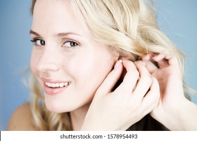 A young woman putting on earrings - Shutterstock ID 1578954493