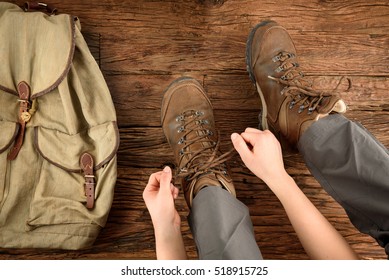 Young Woman Is Putting On Shoes For Hiking On Wooden Floor