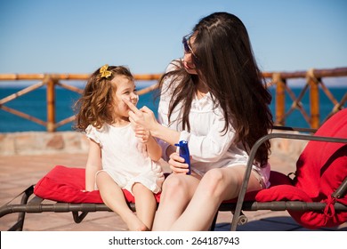 Young Woman Putting Some Sunblock On Her Daughter's Face Before Going Down To The Beach On A Sunny Day