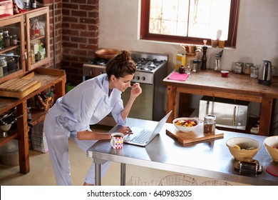 Young Woman In Pyjamas Using Laptop At Breakfast, High Angle