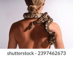 Young woman with python snake elegantly slithering over her neck.