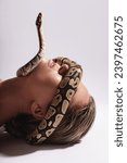 Young woman with a python snake slithering over her face, covering her eyes