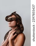Young woman with a python snake slithering over her face, covering her eyes