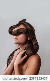 Young woman with a python snake slithering over her face, covering her eyes