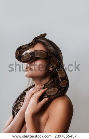 Young woman with a python snake slithering over her face, covering her eyes