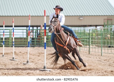 Young woman racing her horse in a rodeo pole bending event.