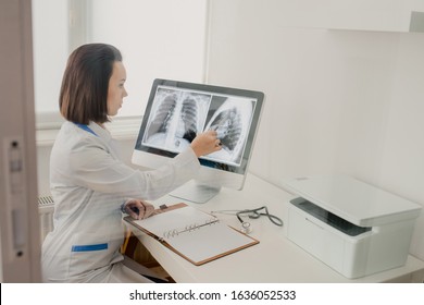 Young Woman Radiologist Doctor Analysis X-ray And Computer Tomography Film And Make A Medical Description In Notebook