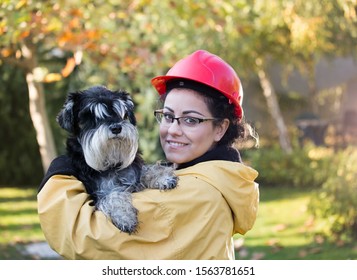 Young Woman In Raincoat And With Helmet Holding Dog. Animal Rescue Concept