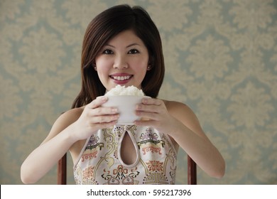 Young Woman Raising Bowl Of Rice Smiling At Camera