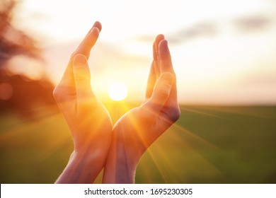 young woman raising hands praying at sunset or sunrise light - Powered by Shutterstock