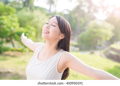 young woman raising her arms and smile to you, nature green background