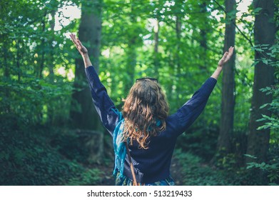 A young woman is raising her arms in the forest - Shutterstock ID 513219433