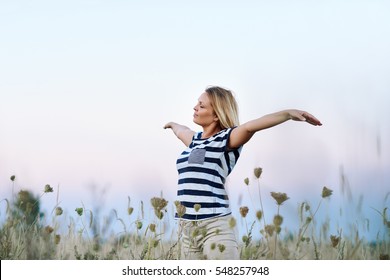 Young Woman Raising Her Arms To The Blue Sky