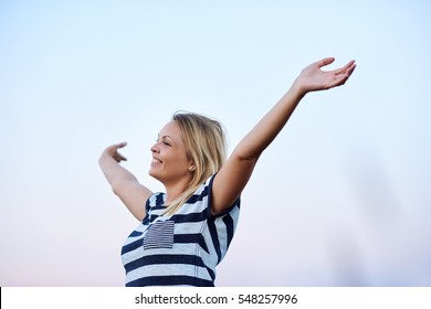 Young Woman Raising Her Arms To Embrace The Sky