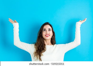 Young Woman Reaching And Looking Upwards On A Blue Background